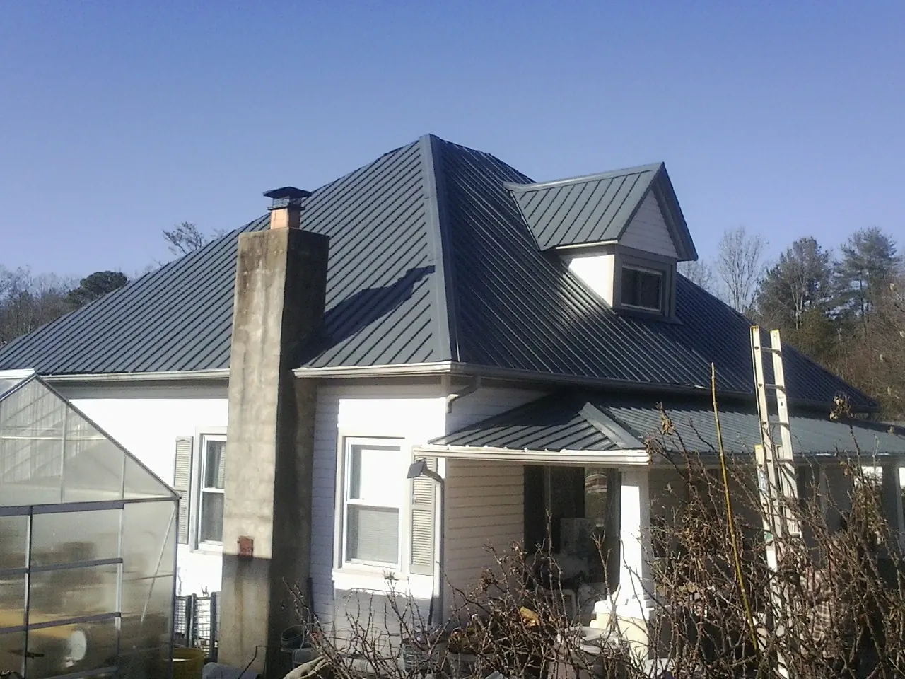 Dark blue standing seam metal roof on a white farmhouse with dormer — Slate & Tile Roof Repair by Roofing Brothers in Cedar City