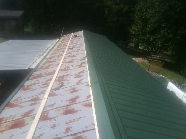 Old rusted panels beside newly installed green metal roofing — Wind Damage Roof Repair by Roofing Brothers in Cedar City