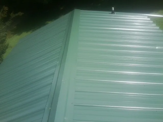 New green metal panels meeting at the ridge of a roof — Flat Roof Repair work by our crew in Cedar City