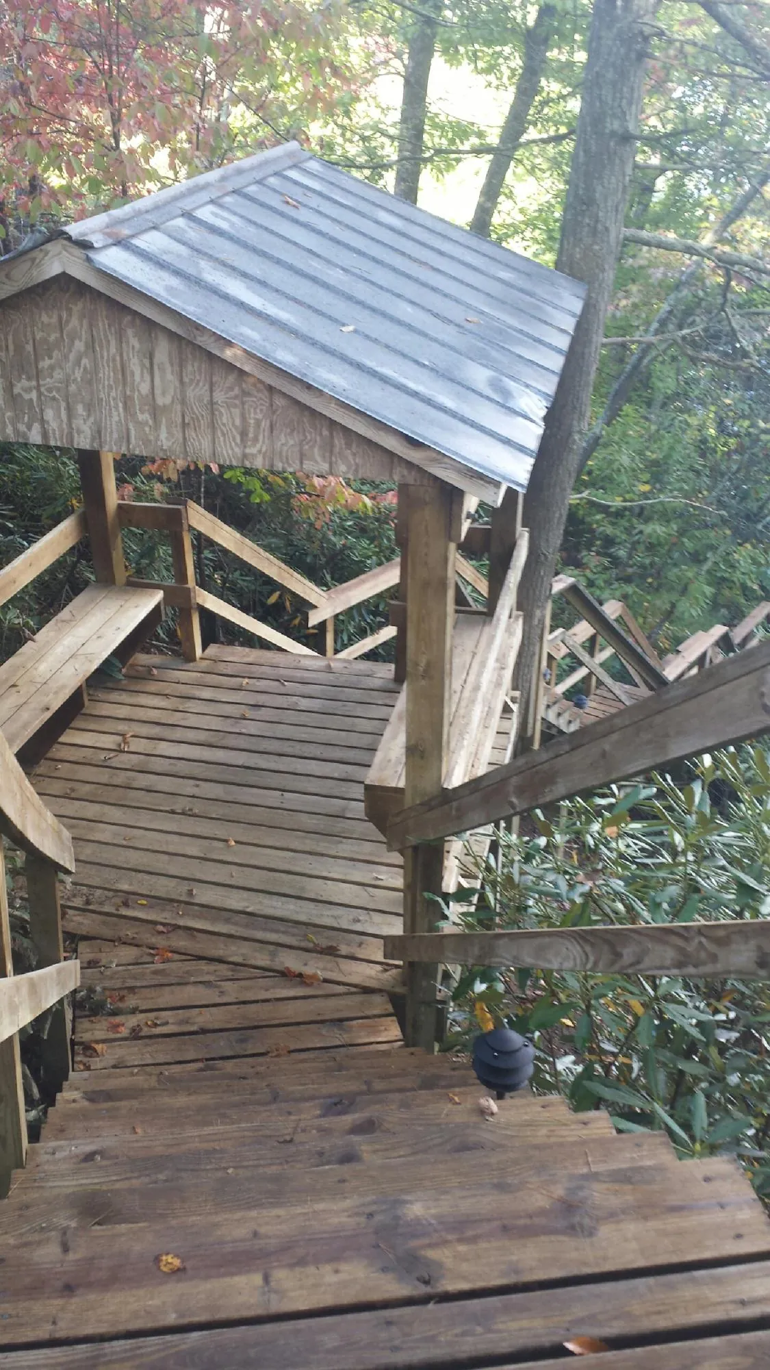Metal roofed shelter over wooden steps on a wooded walkway — Skylight Repair & Installation work by our crew in Cedar City