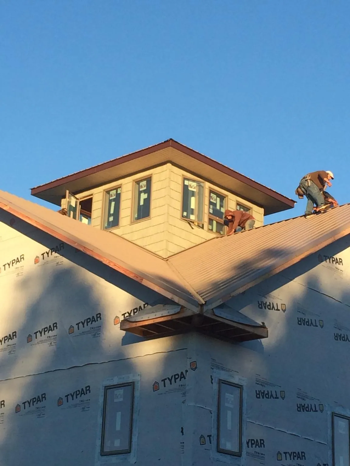 Roofers working around a rooftop cupola on a new metal roof at sunset — Roof Waterproofing in Cedar City by Roofing Brothers